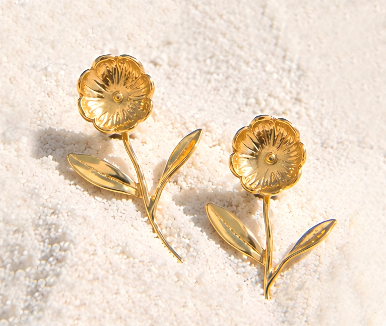 18K gold blossom stem earrings on white sand, summer
