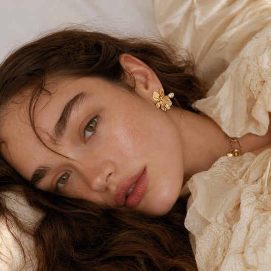Woman wearing Minimal Orchid Bloom Earrings in 18K Gold Plated Brass.